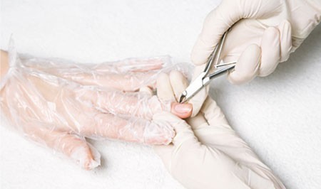 Процесс обрезания кутикулы специальными щипчиками