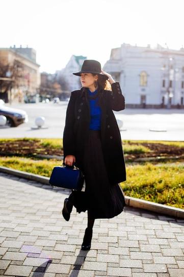Девушка в длинной юбке, шляпе и черном пальто