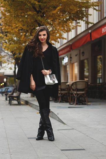 Девушка в сапогах, короткой юбке и черном пальто