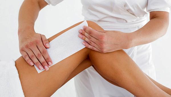Therapist waxing woman s leg at spa center